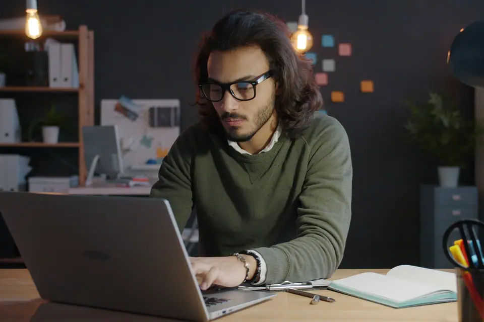 Engineer working on a laptop in a dimly lit office