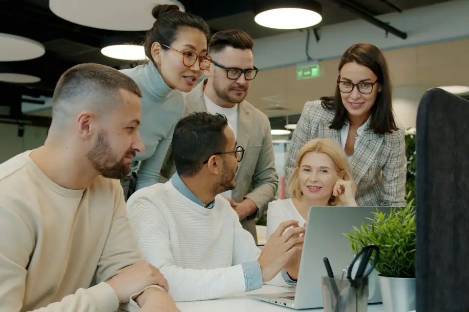Team collaborating around a laptop in a bright modern office