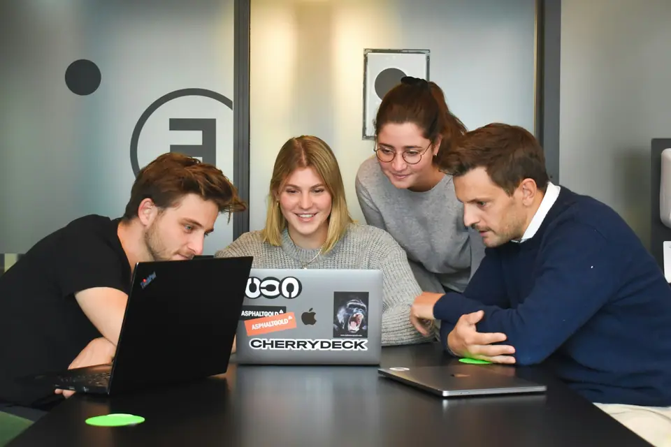 Colleagues laughing together while reviewing work on laptops